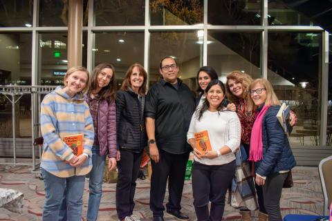 Group of adult readers stand with author, Oscar Hokeah while holding his book, "Calling for a Blanket Dance"