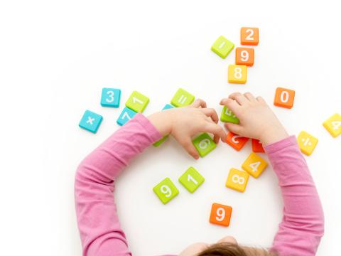 View from above of child's hands playing with colorful number blocks