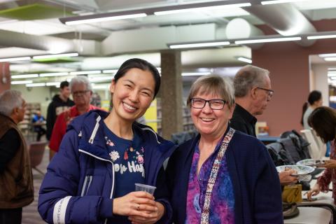 Two women at a library event smile at the camera 