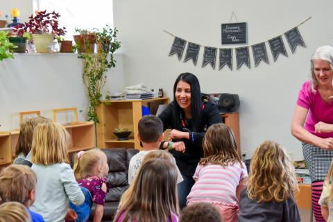 View behind kids facing presenter indoors as they listen to story