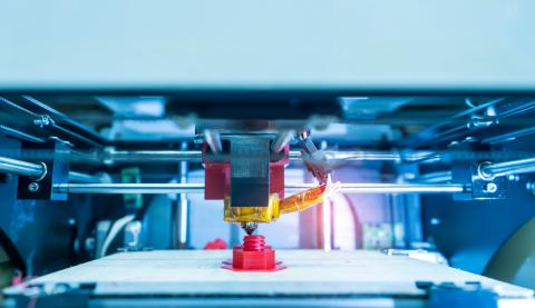 a 3D printer mid process prints a red object