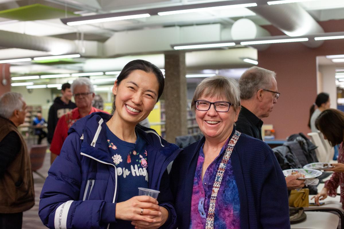 Two women at a library event smile at the camera 